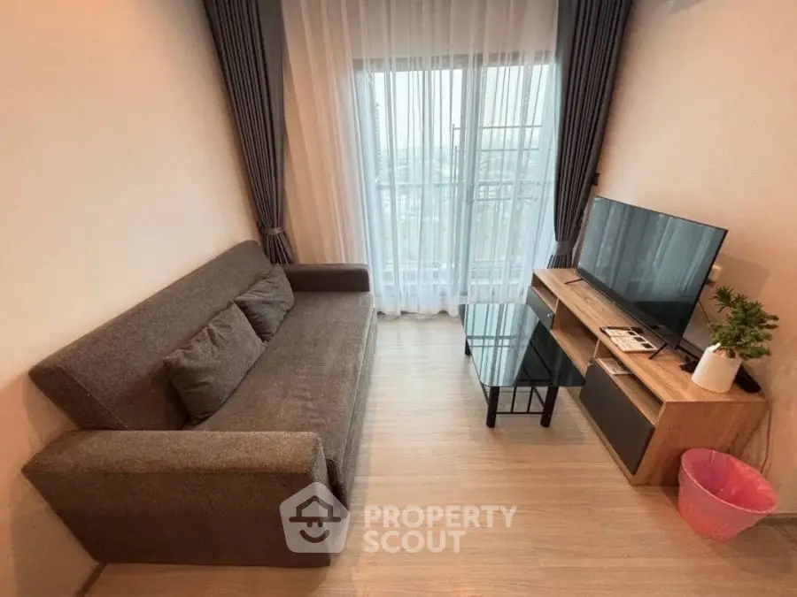 Cozy living room with modern sofa, TV, and balcony view, perfect for relaxation.