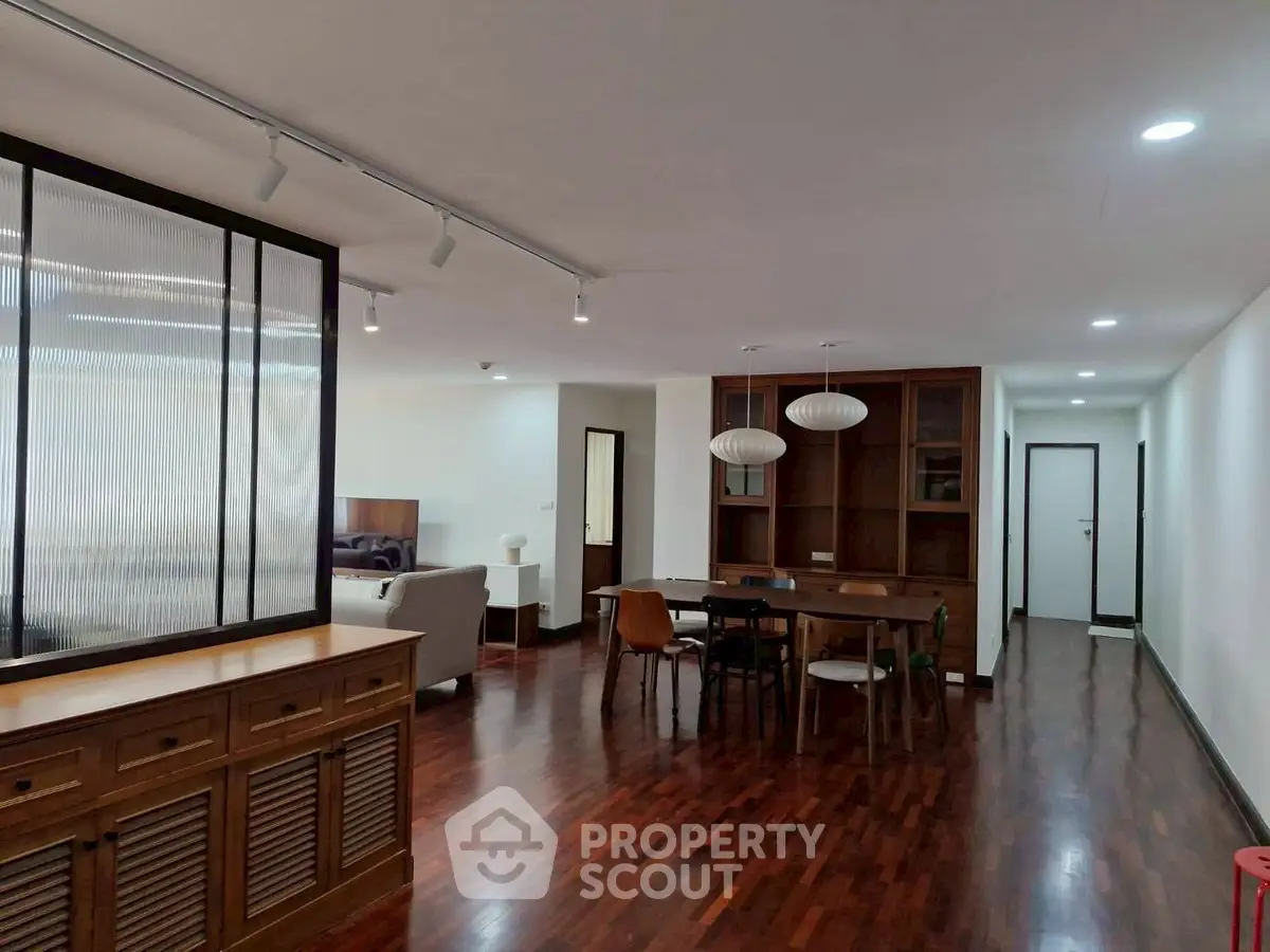 Spacious open-plan living and dining area with modern furnishings and wooden flooring.