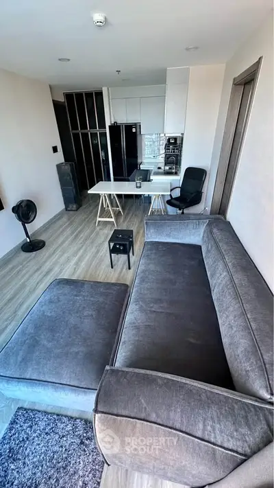Modern living room with sleek grey sofa and open kitchen layout, perfect for urban living.