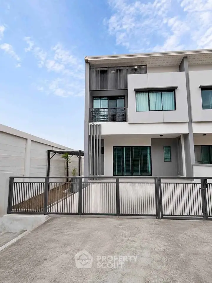Modern townhouse exterior with sleek design and spacious driveway under a clear blue sky.