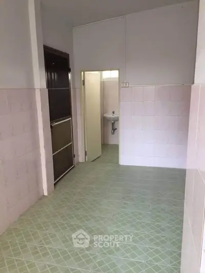 Spacious bathroom with tiled walls and floor, featuring a simple sink and door.