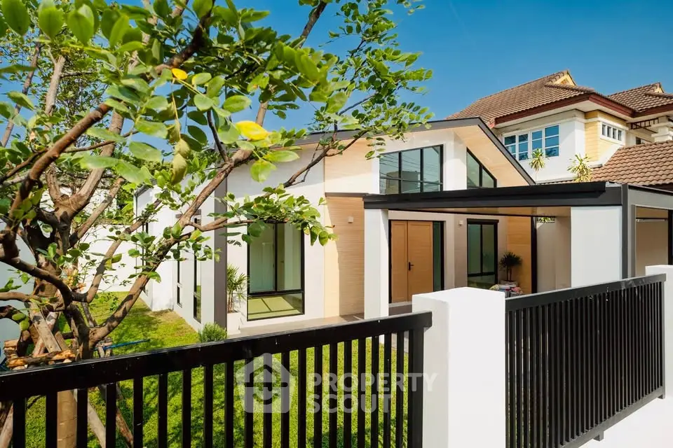Charming modern house with lush garden and sleek fence in sunny neighborhood.