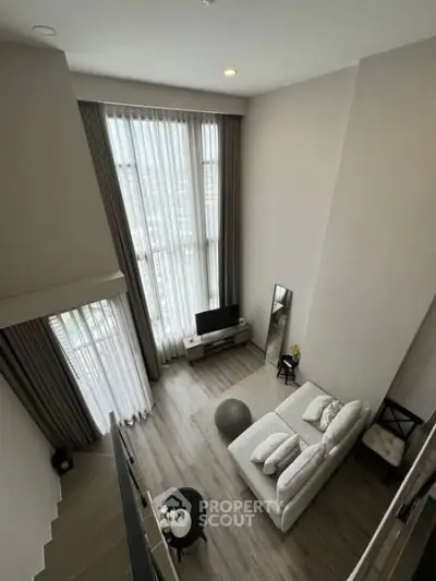 Spacious modern living room with high ceilings and large windows offering abundant natural light.