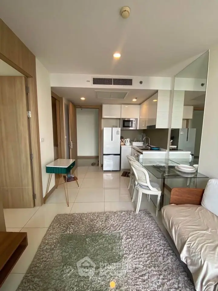 Modern open-layout living room with kitchen, featuring sleek furniture and bright natural lighting.