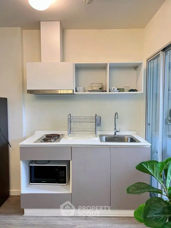 Modern compact kitchen with sleek cabinetry and built-in microwave