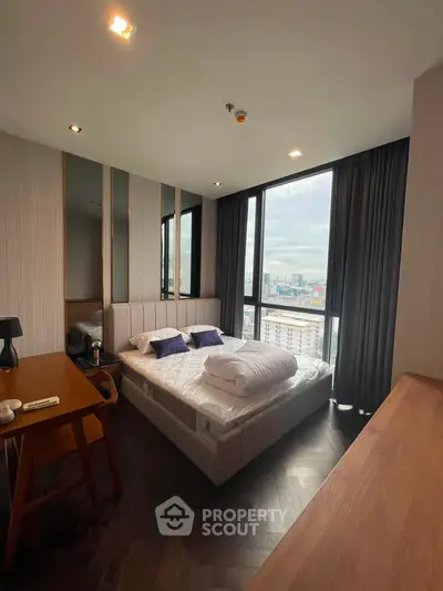 Modern bedroom with city view, featuring stylish decor and large windows for natural light.