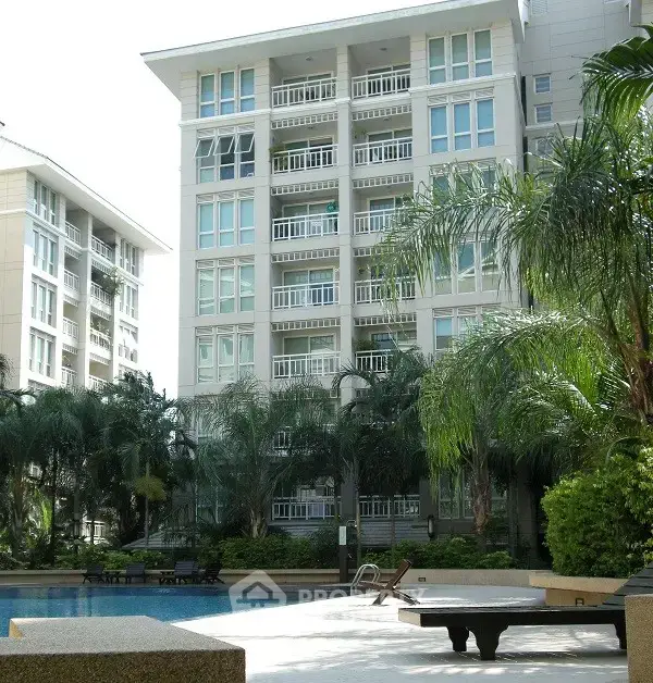 Luxurious apartment building with pool and lush greenery, perfect for modern living.