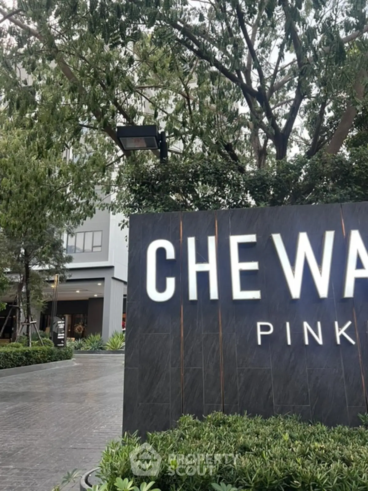 Modern residential building entrance with lush greenery and stylish signage
