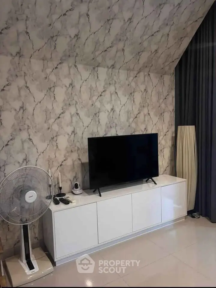 Modern living room with stylish marble wall, sleek TV unit, and elegant floor lamp.