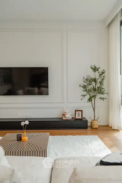Elegant living room with modern decor, large TV, and stylish furnishings.