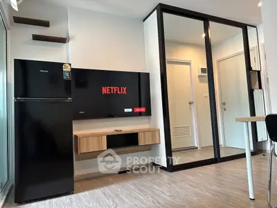 Modern living room with sleek TV setup and mirrored wardrobe in stylish apartment.
