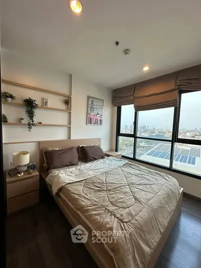 Modern bedroom with city view, featuring cozy bedding and stylish decor.
