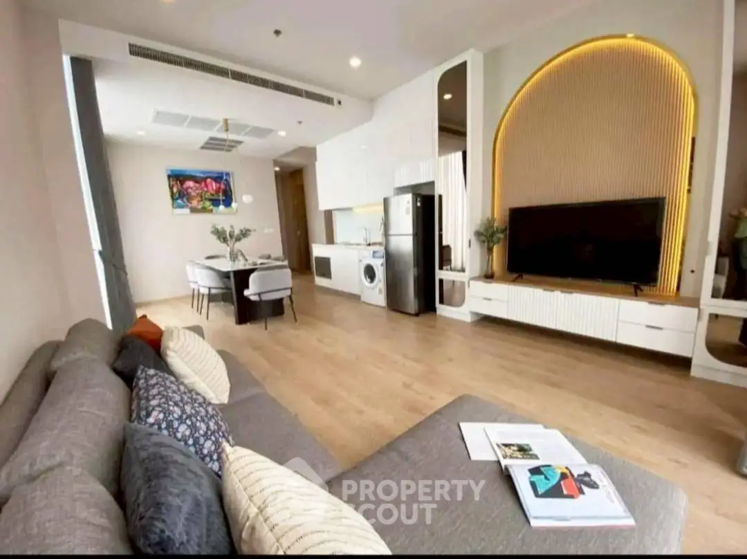 Modern living room with open kitchen, stylish decor, and cozy seating area.