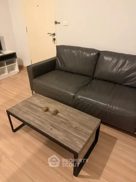 Modern living room with sleek leather sofa and stylish wooden coffee table.