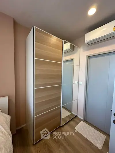 Modern bedroom with sleek wardrobe and air conditioning unit, showcasing stylish and functional design.