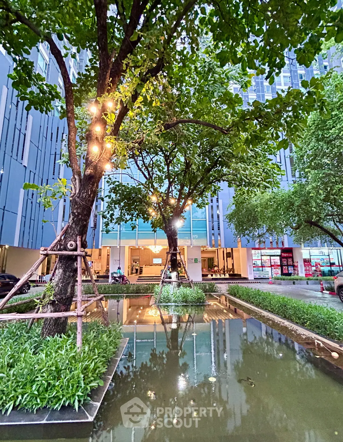 Modern building entrance with lush greenery and decorative lighting