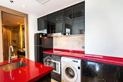 Modern kitchen with red countertops, washing machine, and sleek black cabinets.