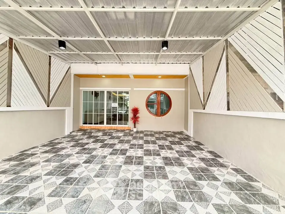 Modern covered parking area with stylish geometric tile design and unique circular window feature.