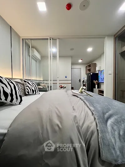 Modern bedroom with stylish decor and sliding glass doors, featuring cozy bedding and ambient lighting.