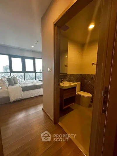 Modern apartment with cozy bedroom and compact bathroom, featuring city views.