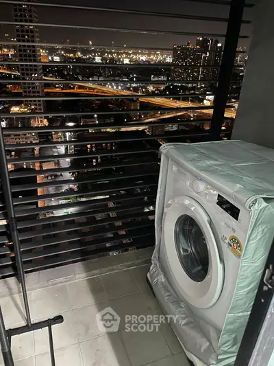 High-rise balcony with washing machine and stunning city night view.