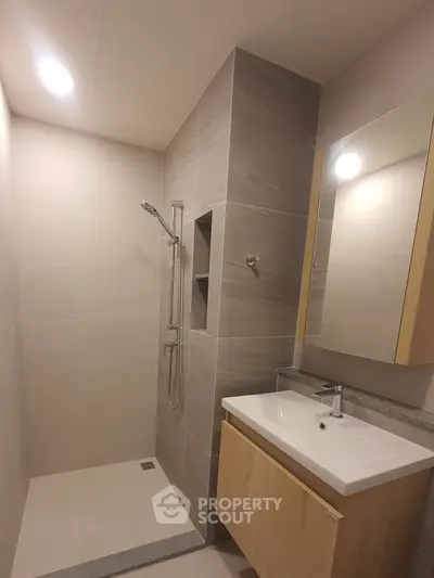 Modern bathroom with sleek shower and elegant vanity in neutral tones.
