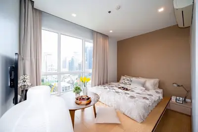Modern bedroom with city view, featuring cozy decor and natural light.