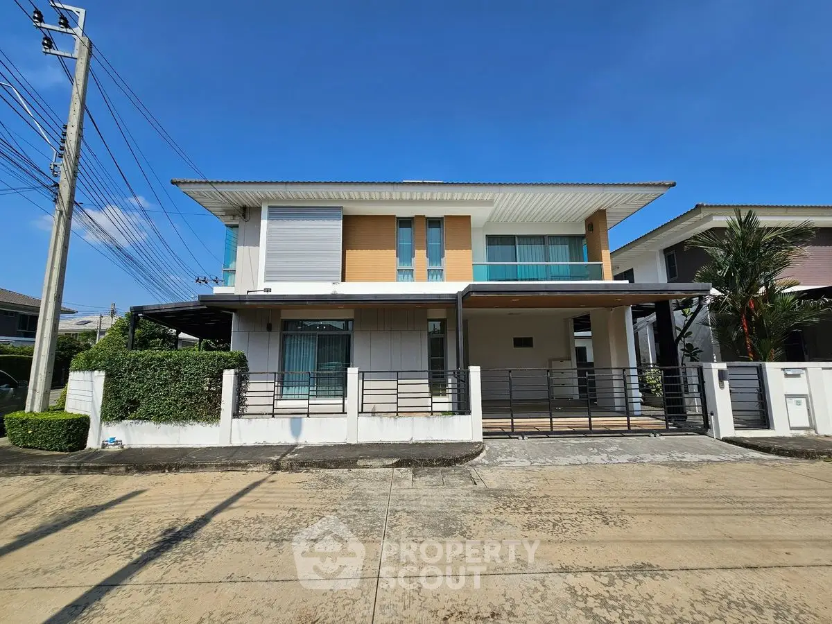 Modern two-story house with sleek design and spacious balcony in a suburban neighborhood.