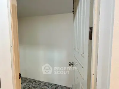 Minimalist interior space with open door and tiled floor, ideal for storage or utility use.
