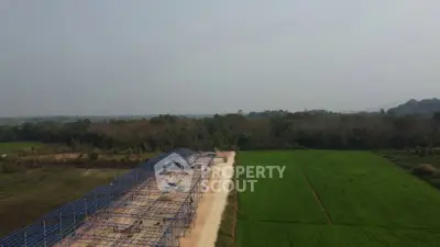 Expansive construction site with steel framework amidst lush greenery