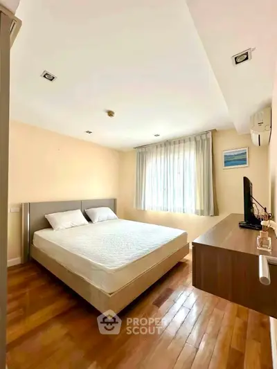 Bright and cozy bedroom with wooden flooring and modern furnishings in a stylish apartment.