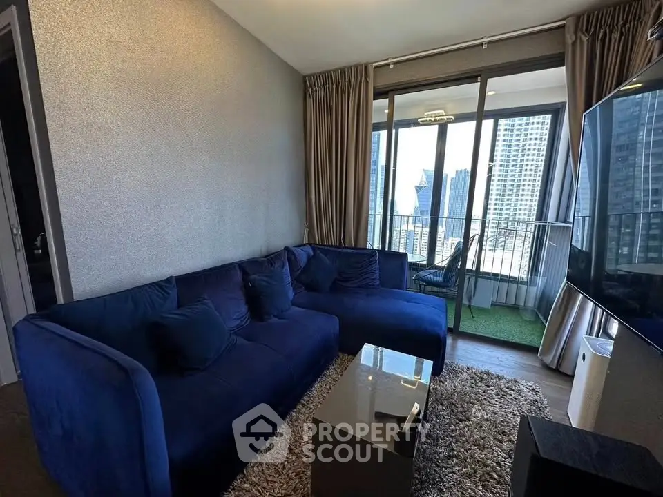 Modern living room with blue sofa and city view balcony in high-rise apartment