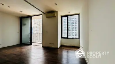 Spacious modern apartment with wooden flooring and balcony view in urban high-rise.