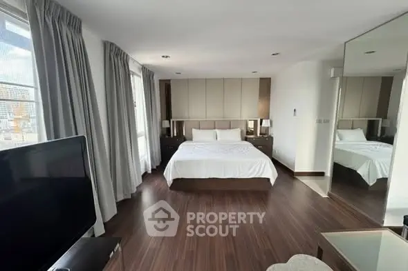 Spacious modern bedroom with elegant decor and large windows offering natural light.