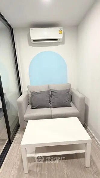 Modern living room with gray sofa, white coffee table, and air conditioning unit.