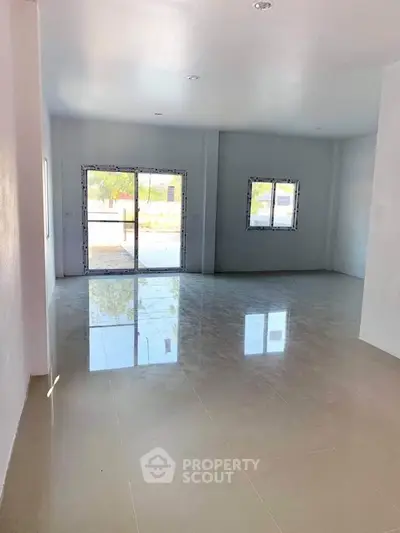 Spacious empty room with large windows and glossy tiled floor