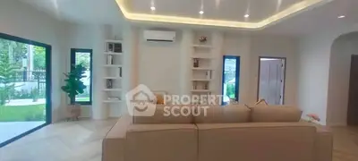 Spacious living room with modern design and garden view, featuring elegant lighting and cozy seating.