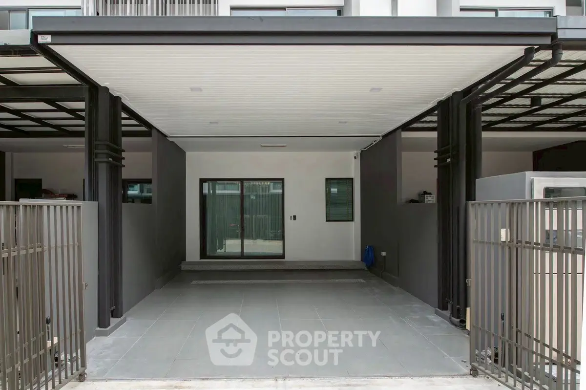 Modern covered parking space with sleek design and gated entrance in urban residential building.