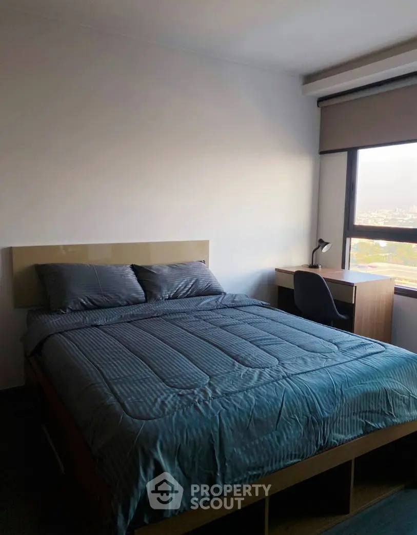 Cozy bedroom with a comfortable bed and study desk, featuring a large window with city views.