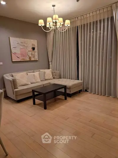 Elegant living room with cozy sofa, chic chandelier, and floor-to-ceiling curtains for a luxurious ambiance.