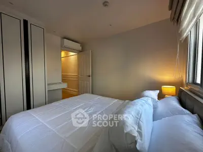 Cozy bedroom with modern decor and ample natural light, featuring a comfortable bed and stylish wardrobe.