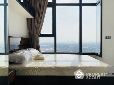 Luxurious bedroom with floor-to-ceiling windows offering panoramic city views, complemented by modern furnishings and a plush bed ready for a restful night.