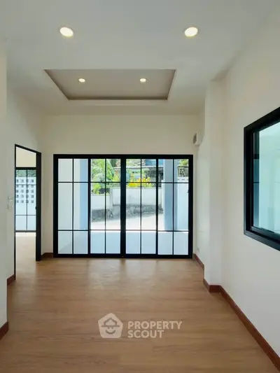 Spacious modern living room with large glass doors opening to a bright outdoor area.