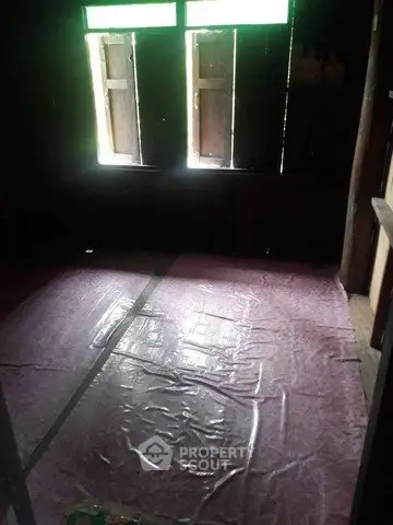 Dimly lit room with plastic-covered floor and wooden windows
