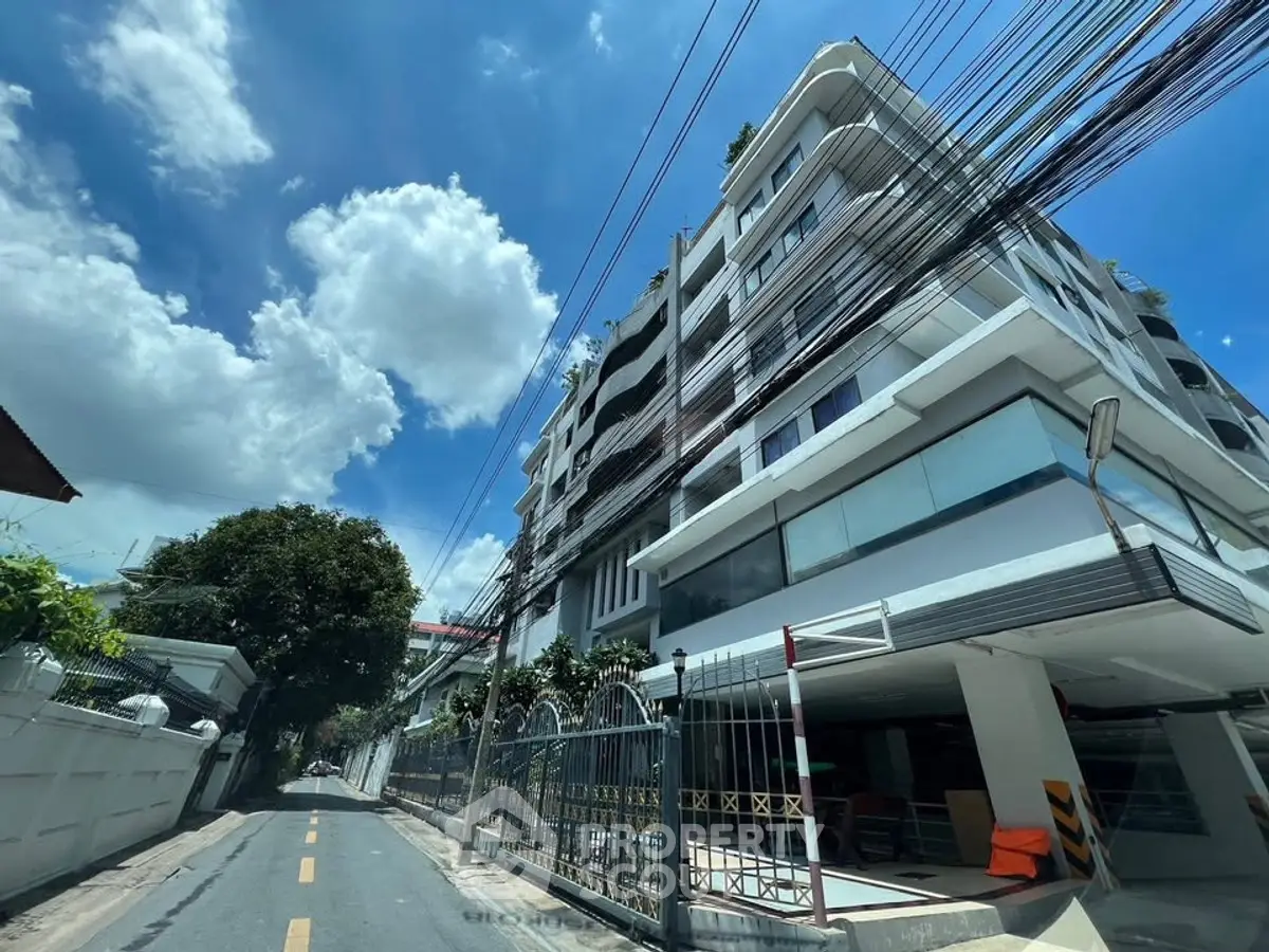 Modern multi-story building with sleek design on a sunny day, showcasing urban living.