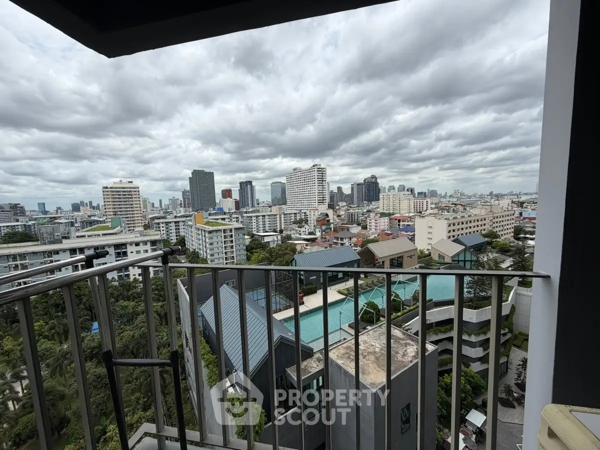 Stunning cityscape view from a high-rise balcony overlooking urban skyline and lush greenery.