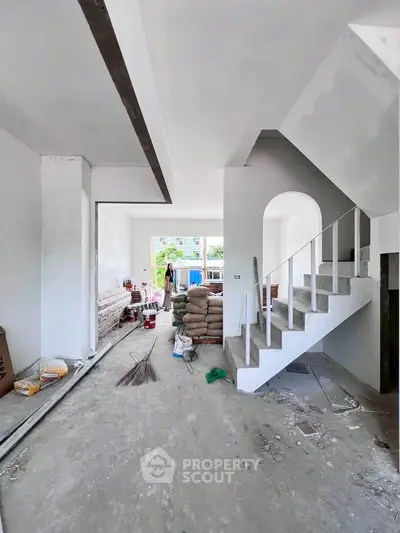 Spacious under-construction living room with modern staircase and large windows
