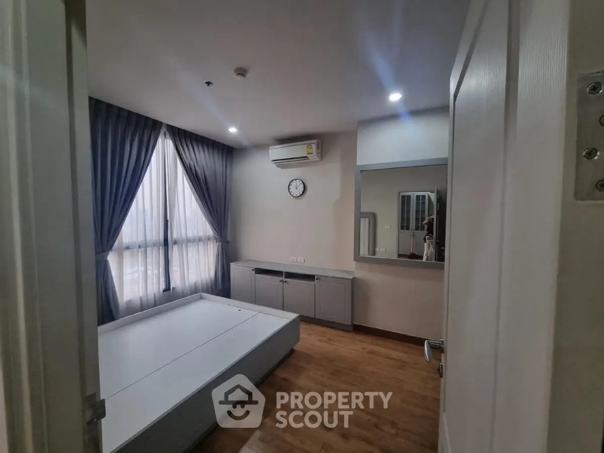 Modern bedroom with wooden flooring, large window, and air conditioning unit.