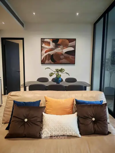 Stylish living room with modern decor and elegant dining area, featuring plush cushions and contemporary artwork.
