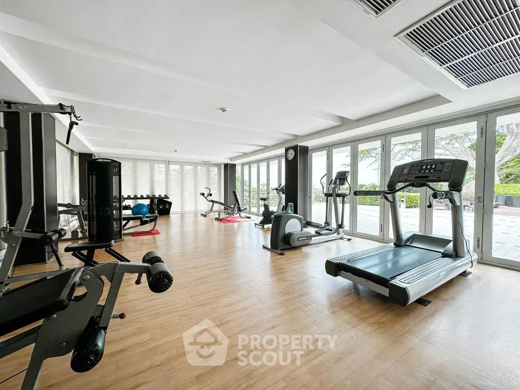 Spacious modern gym with state-of-the-art equipment and large windows offering natural light.